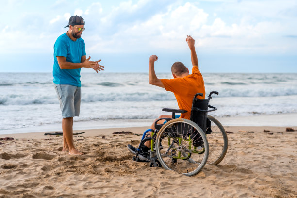 一个坐在轮椅上的残疾人在海滩上笑着，在海边玩得很开心图片下载