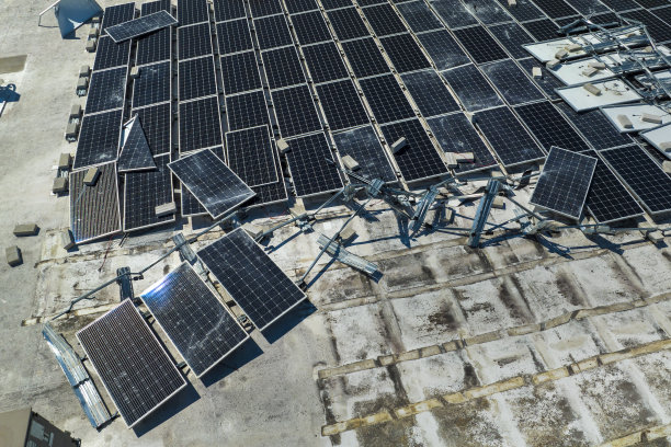 被飓风“伊恩”摧毁的光伏太阳能电池板安装在工业建筑屋顶上，产生绿色生态电力。自然灾害的后果图片下载