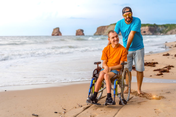 海边的朋友推着一个坐在轮椅上的残疾人图片下载