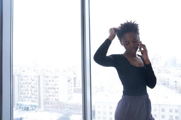 一位穿着运动服的年轻黑人女性正在使用手机，目光移开。一个不满意的短发年轻女人。生活方式照片与复制空间。高质量照片图片下载