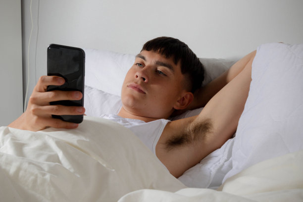 躺在床上玩电话的年轻人图片下载
