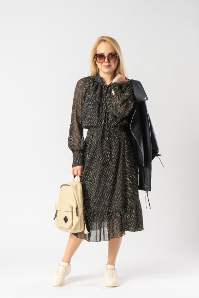 一位戴着太阳镜、穿着休闲装的女士手里拿着一件夹克和背包图片下载