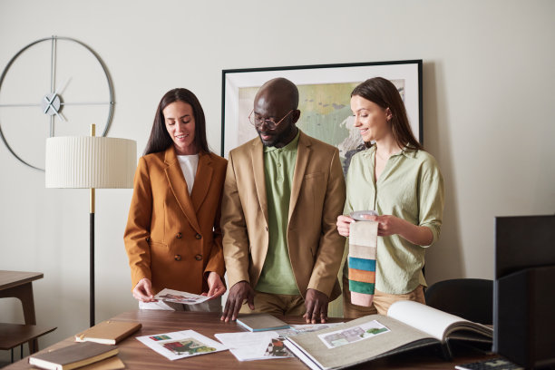 三位年轻的跨文化设计师正在看室内设计的草图或照片图片下载