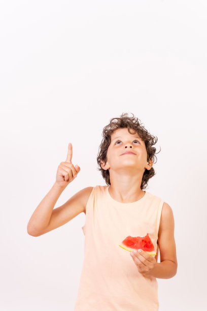 男孩吃着西瓜，指指点点，暑假到了。白色背景与复制粘贴图片下载