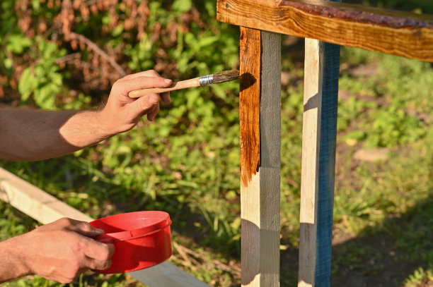 一个人给木头涂上一层涂料。在花园里图片下载