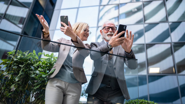 穿着西装的高级男子和成熟的金发女子作为商业伙伴，夫妻朋友或同事聊天，手里拿着智能手机浏览互联网，看照片，交换意见，复制空间图片下载