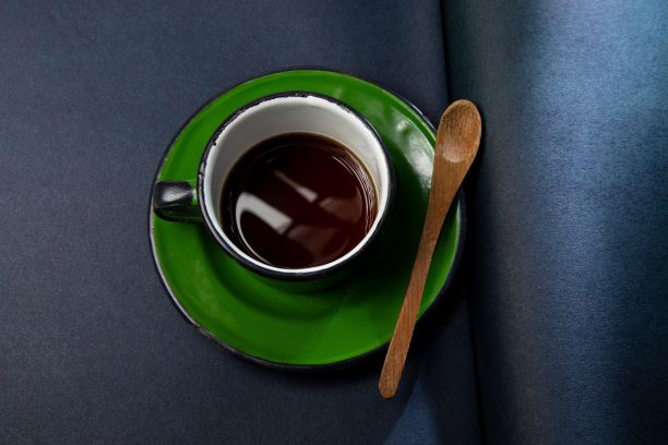 头顶上的库存照片，一个陶瓷杯装满了咖啡，勺子搁在它的边缘图片下载