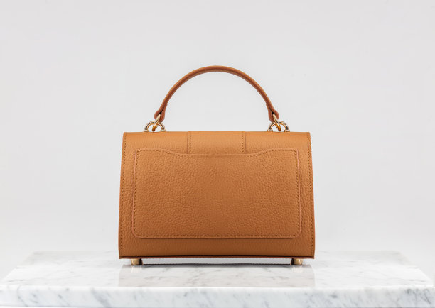 奢侈女包。白色背景的豪华橙色皮革手袋，大理石地板。图片下载