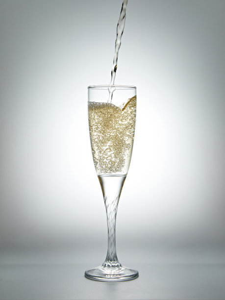 把香槟酒倒进灰色背景的玻璃杯里。图片下载
