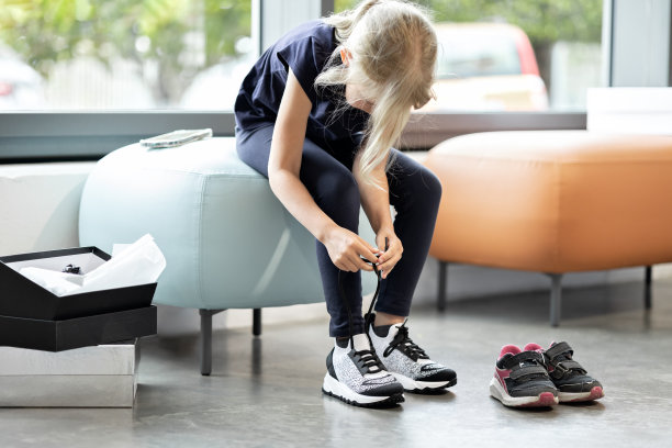 孩子在商店里一边系鞋带一边试穿运动鞋图片下载