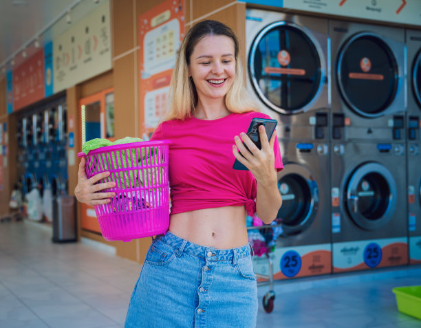 年轻漂亮的女人在洗衣房打电话图片下载