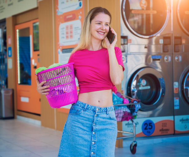 年轻漂亮的女人在洗衣房打电话图片下载