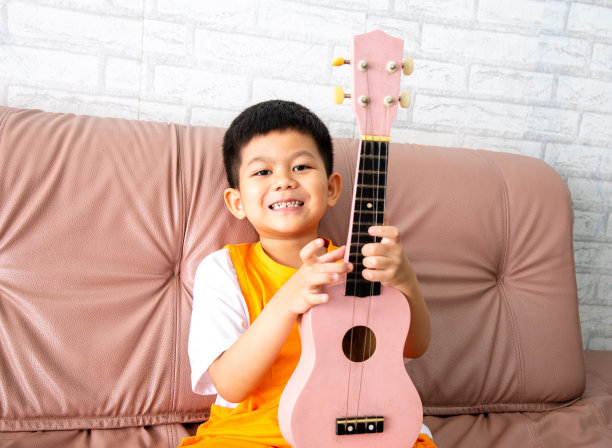 一个快乐的男孩在家里的房间里弹着原声吉他。图片下载