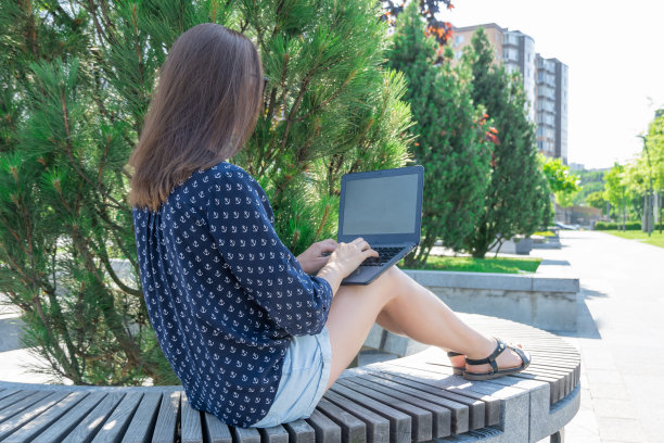 在城市公园用手提电脑工作的自由职业者。图片下载