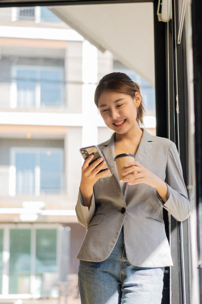 成功的年轻亚洲女性在工作间隙用手机聊天。当你站在广告文本或促销材料的复制空间附近时图片下载