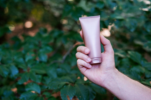 拿着米色面霜筒的男子以自然为背景。设计模型图片下载