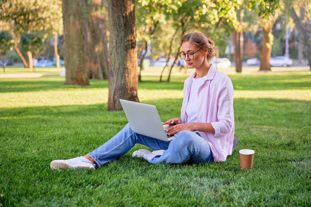 女商人坐在草地夏日公园使用笔记本电脑商务人士远程工作。户外图片下载