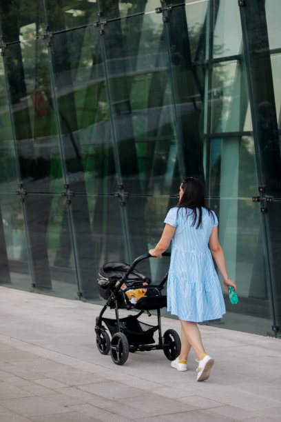 妈妈和宝宝推着婴儿车和一瓶水走着图片下载