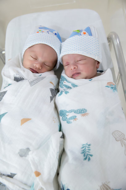 刚出生的双胞胎睡觉。新生儿双胞胎睡在床上。可爱的新生儿睡在床上。图片下载