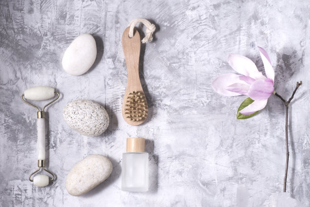 面部和身体护理平铺玉兰花，有机化妆品，生态友好，按摩石，按摩辊，身体刷，零浪费，灰色混凝土背景图片下载