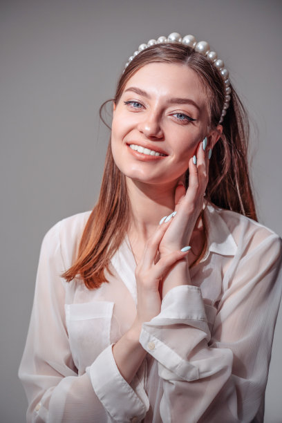 时髦的年轻女子穿着白色休闲服装，看着别处微笑着。图片下载