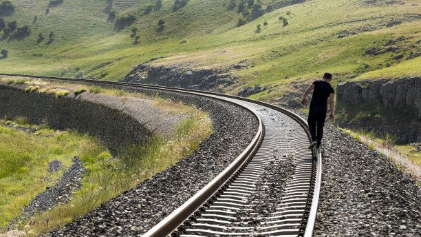 男子尝试走在铁轨上的主观视角，无人机侧拍，背景是河流图片下载