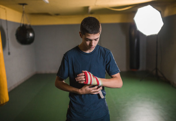在拳击馆开始训练前，一名拳手在手上缠上防护绷带图片下载