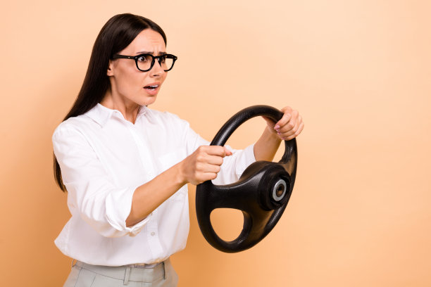 照片中震惊的女士戴着白衬衫眼镜驾驶车辆，看着空旷孤立的米色背景图片下载