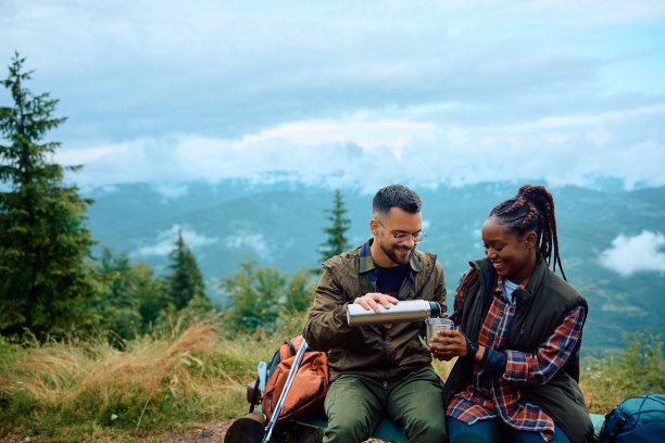 幸福的多种族夫妇在大自然中徒步旅行时喝水。图片下载