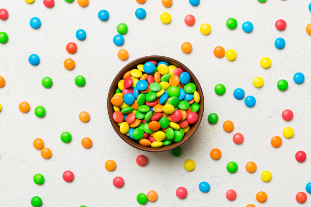五颜六色的糖果放在碗里，背景是彩色的。生日和节日的概念。带复制空间的俯视图图片下载