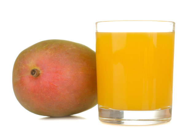 成熟的新鲜芒果果实和芒果汁在一个杯子里，白色孤立的背景。热带水果图片下载