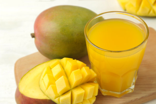 成熟的新鲜芒果水果和芒果汁，在浅背景的杯子。热带水果图片下载