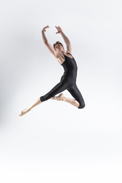 芭蕾舞演员年轻的白人运动员在黑色西装在白色的工作室摆姿势跳舞。图片下载