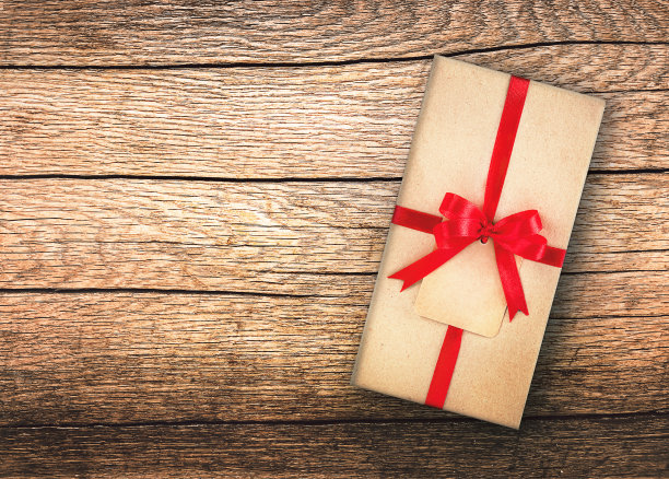 桌子上放着一个手工包装的礼物，上面有一个红色的丝绸蝴蝶结。文本空间图片下载