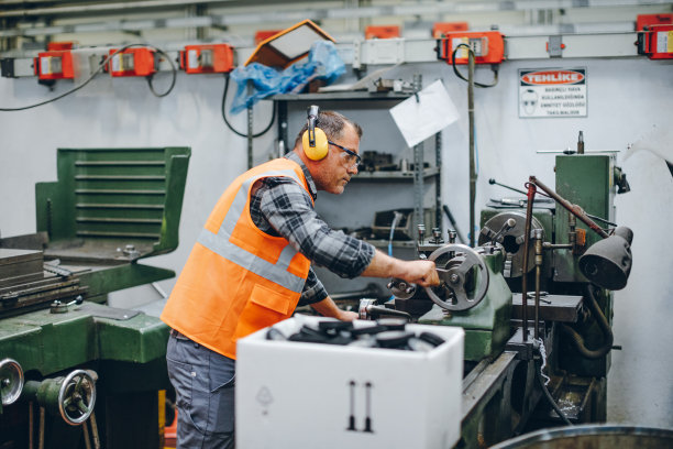 在工厂里与铣床一起工作的车床工人图片下载