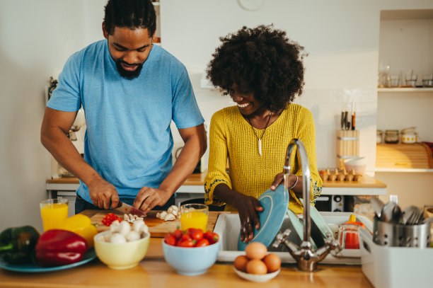 一对非裔美国夫妇正站在厨房里准备从家里带回来的午餐。图片下载