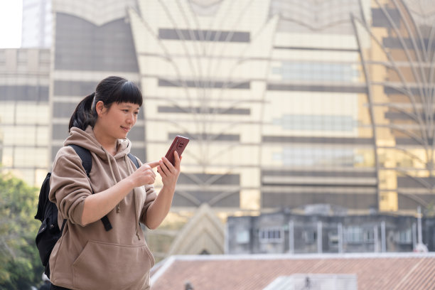 一名女游客站在澳门街头，看着她的手机图片下载
