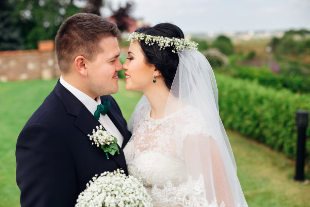 新婚夫妇拥抱并想要亲吻。新娘手持结婚花束图片下载