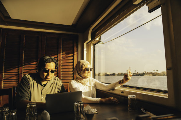 快乐的穆斯林夫妇在尼罗河日落时乘船旅行，开罗图片下载