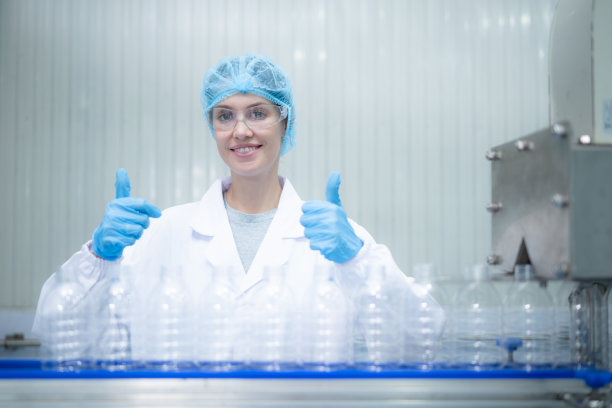 女质检员在饮水厂的生产线上检查水瓶图片下载