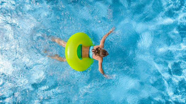 活跃的年轻女孩在游泳池空中俯瞰从上面看，青少年放松和游泳的充气环甜甜圈，并在水中享受乐趣的家庭度假，热带度假胜地图片下载