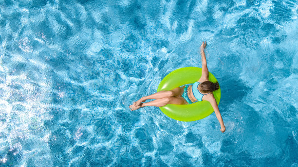 活跃的年轻女孩在游泳池空中俯瞰从上面看，青少年放松和游泳的充气环甜甜圈，并在水中享受乐趣的家庭度假，热带度假胜地图片下载