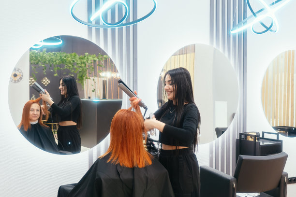 现代时尚美容院。女发型师为客户做头发和发型。美丽的东方黑发女郎在美发沙龙工作图片下载