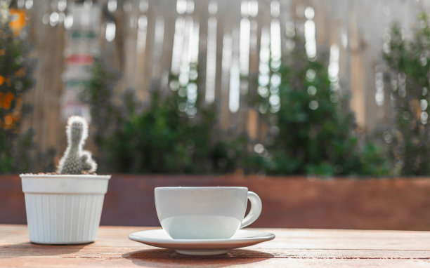 在早晨的阳光下，在木桌上喝一杯咖啡图片下载