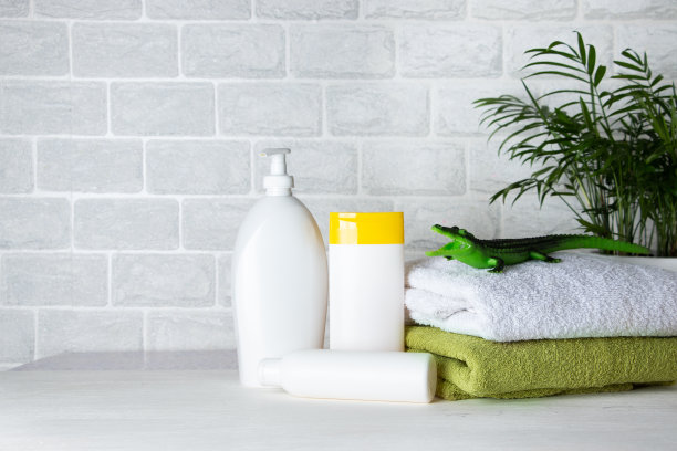 婴儿沐浴用品，毛巾，绿色橡胶鳄鱼皮和洗发水瓶。儿童保育的概念。图片下载