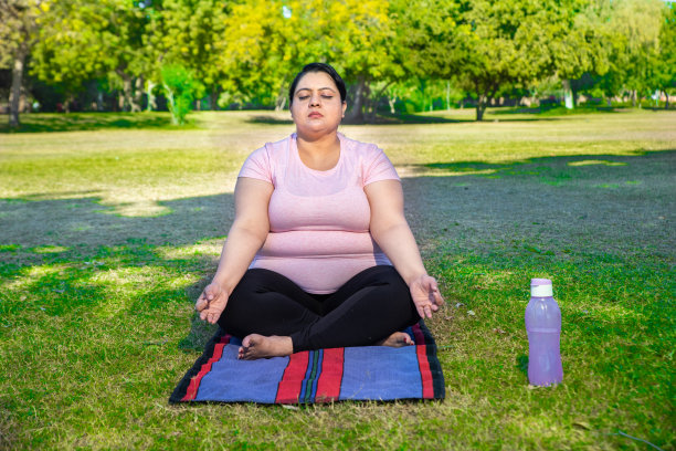 超重的印度妇女在公园户外做瑜伽冥想练习。肥胖女性健身生活方式。全裸镜头。图片下载