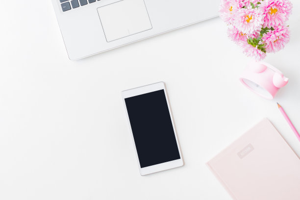 扁平的家庭办公桌面与笔记本电脑，粉红色的花在一个花瓶，笔记本，平板电脑，办公用品在一个浅色的背景。顶视图样机平板与黑屏图片下载