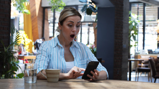 年轻可爱的女人使用手机的特写，拿着智能手机，坐在咖啡馆里回复短信的照片，电话，信件，instagram，室内肖像，帖子。图片下载