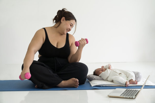 快乐微笑的亚洲年轻母亲在瑜伽垫上锻炼，在家照顾她的新生儿图片下载