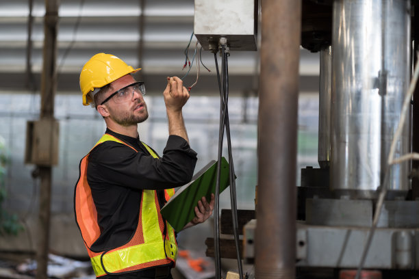在工厂检查、修理、维护数控机床的电气系统。男性电工工程师在制造过程中检查质量电气图片下载